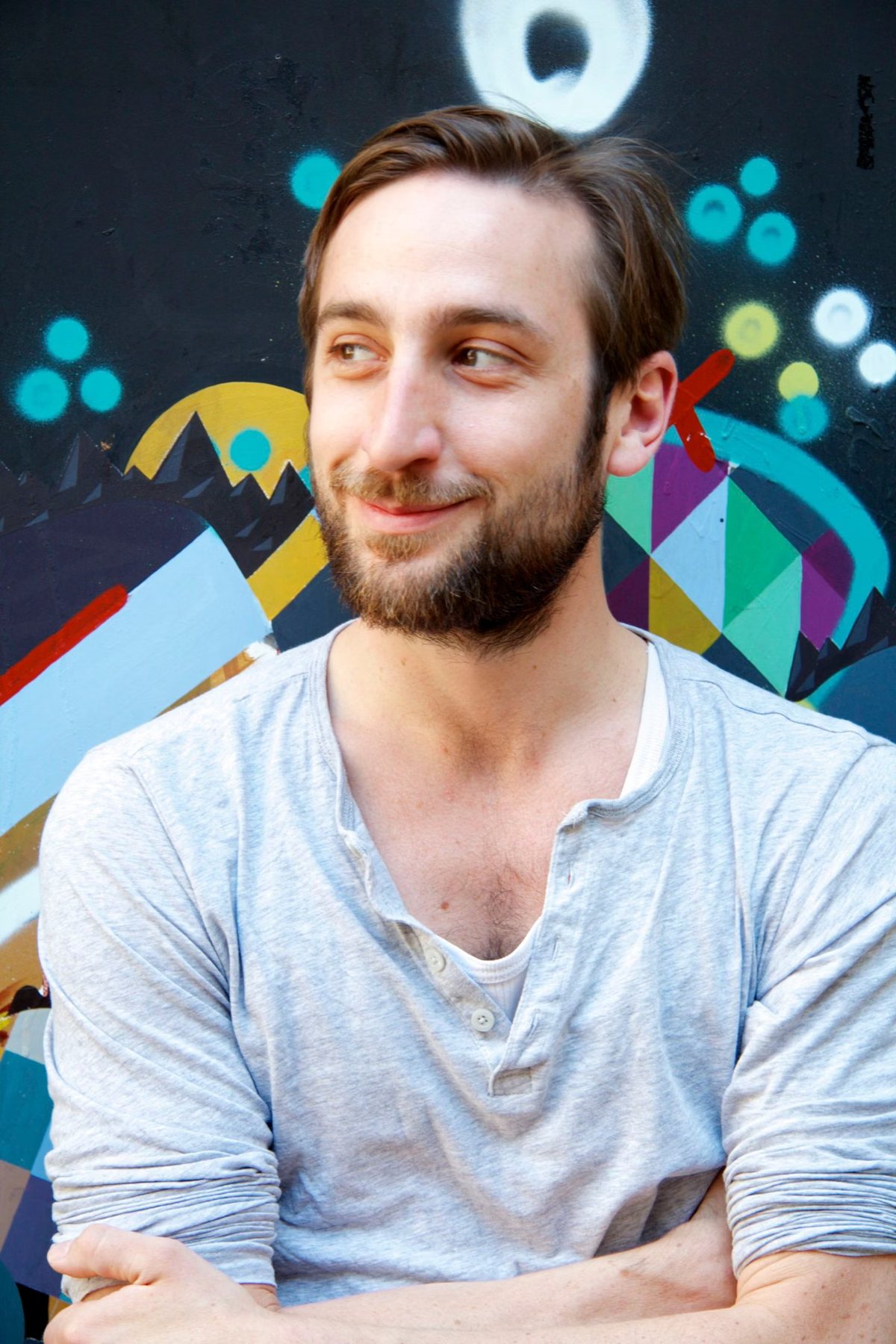 Portrait von Walter Schmuck vor einer bunten Graffitiwand, mit verschränkten Armen